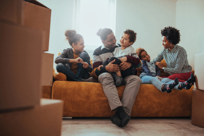 Family sits together on couch after moving into new home purchased a Fannie Mae loan program.