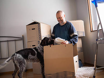 A man opening boxes with a dog