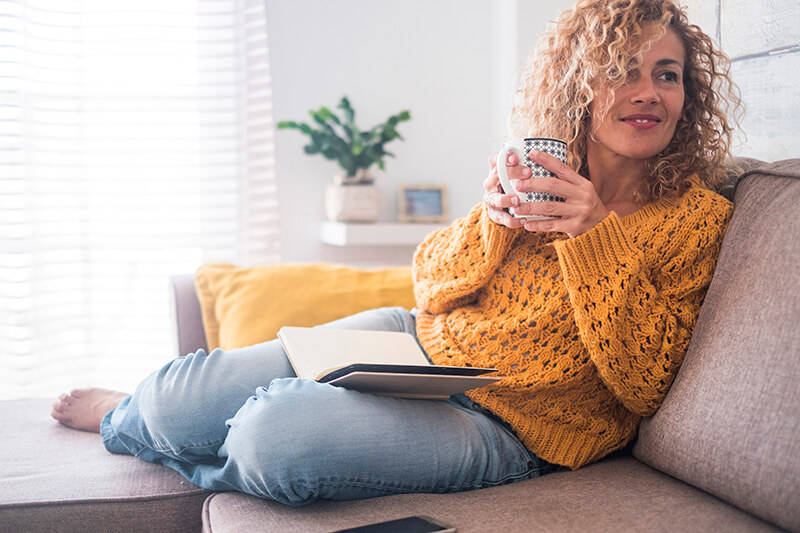 A woman drinking coffee on her couch