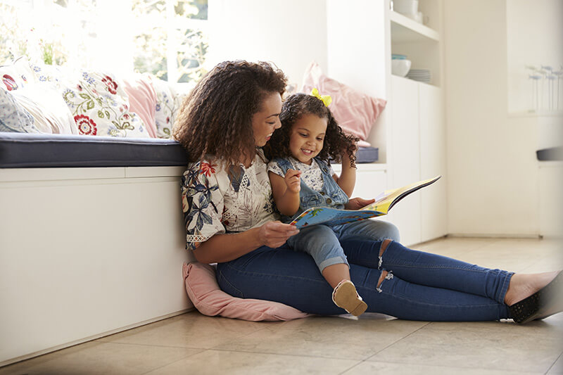A woman and her daughter reading on the floor
