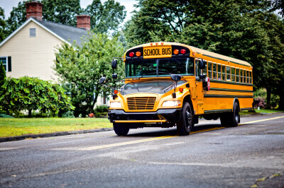 Yellow school bus for local school district driving through neighborhood.