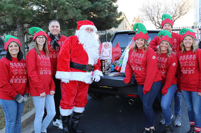 CrossCountry Mortgage employees and Santa standing around the toy donations for Operation Giving Tree