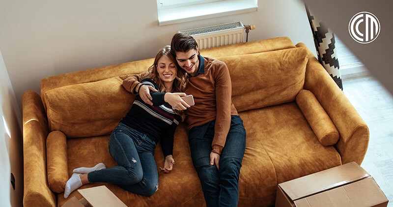 First-time homebuyers smiling on the couch in their new home