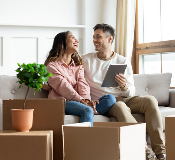 new homeowners sitting in their living room surrounded by moving boxes